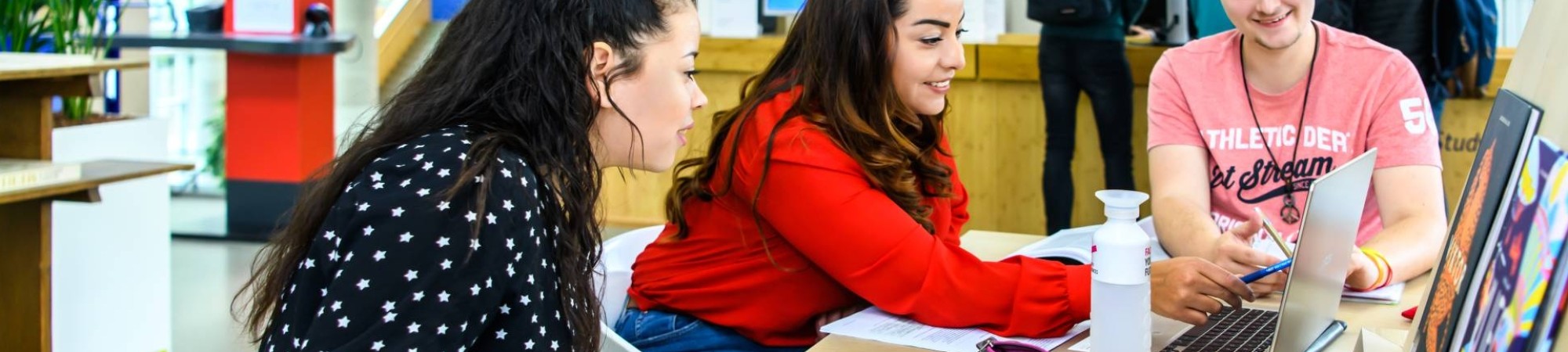 Drie studenten werken op één laptop in de open werkruimte in het I/O gebouw. 